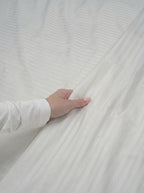 Hand resting on the Picarde Form duvet cover to show the fine ribbed surface texture