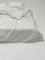 Close view of the Picarde Form duvet cover and pillow in white, showing the striped weave
